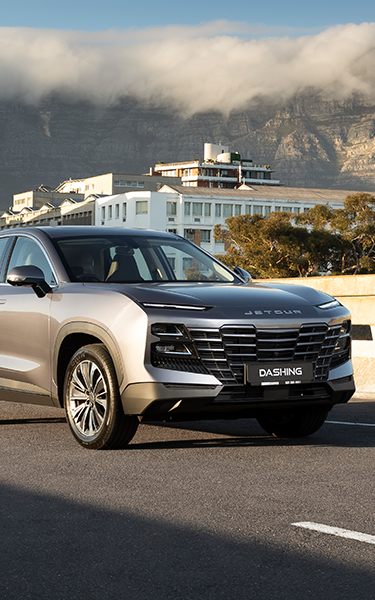 A sleek silver SUV parked against a scenic backdrop of mountains and a lake, showcasing modern design and elegance.