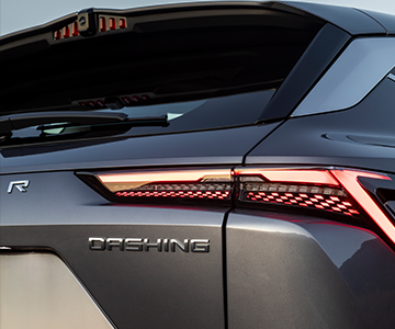 Close-up of a car's stylish rear, showcasing sleek taillights and the "DASHING" badge on a modern, gray vehicle.